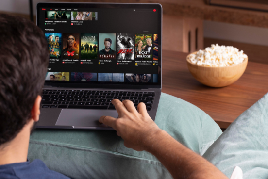 Pessoa assistindo conteúdo do SKY+ em notebook no conforto de casa